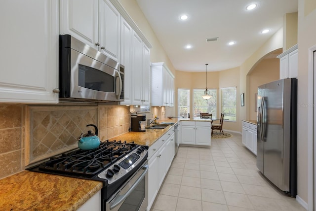 kitchen with decorative light fixtures, white cabinetry, backsplash, appliances with stainless steel finishes, and light tile floors