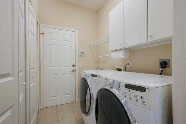 laundry room featuring cabinets, washing machine and clothes dryer, light tile floors, and electric dryer hookup