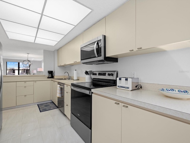 kitchen featuring light tile flooring, an inviting chandelier, appliances with stainless steel finishes, sink, and cream cabinets