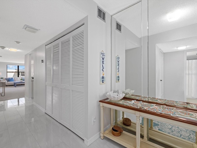 corridor with light tile floors and a textured ceiling