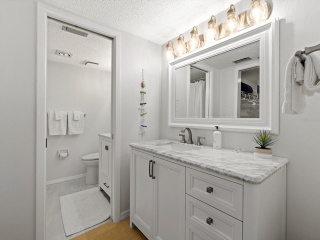 bathroom featuring a textured ceiling, tile floors, large vanity, and toilet