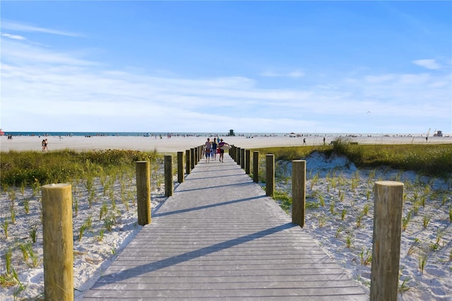 view of dock featuring a water view and a beach view