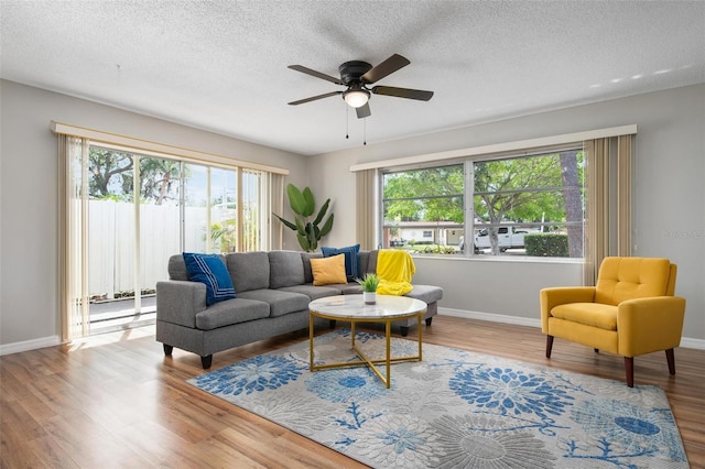 living room with light hardwood / wood-style flooring, ceiling fan, a textured ceiling, and a wealth of natural light