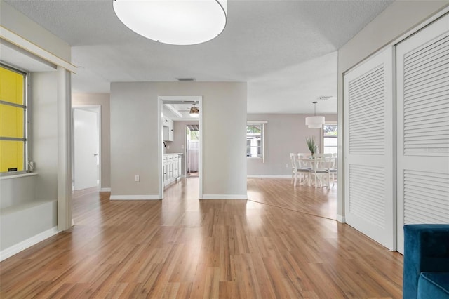 interior space featuring a textured ceiling, ceiling fan, and light wood-type flooring