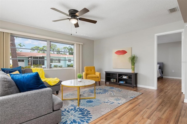 living room featuring ceiling fan, a textured ceiling, and hardwood / wood-style floors