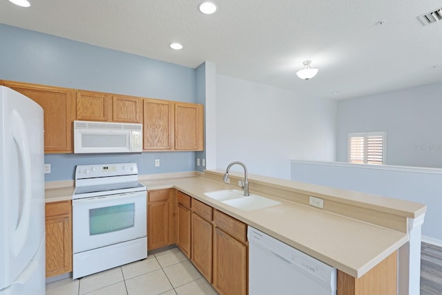 kitchen featuring light tile patterned floors, kitchen peninsula, sink, and white appliances