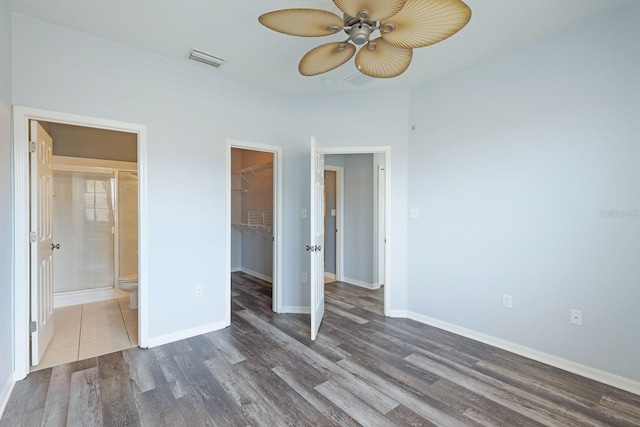 unfurnished bedroom featuring a spacious closet, ceiling fan, connected bathroom, dark hardwood / wood-style floors, and a closet