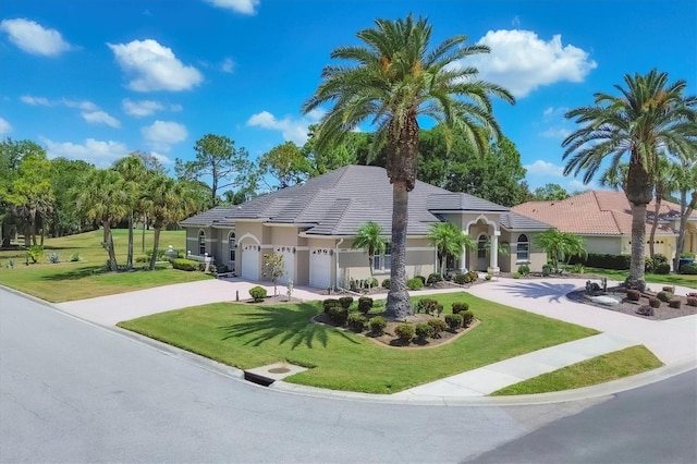 mediterranean / spanish house featuring a garage and a front lawn