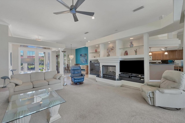 carpeted living room with ceiling fan, built in features, and ornamental molding