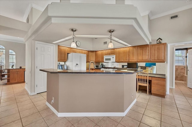 kitchen with a center island with sink, light tile patterned flooring, decorative light fixtures, and white appliances