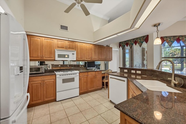 kitchen featuring ceiling fan, sink, hanging light fixtures, dark stone countertops, and white appliances