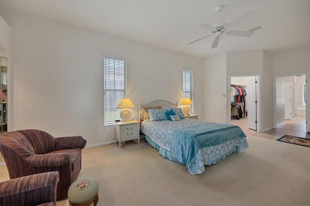 bedroom with light carpet, ceiling fan, a spacious closet, connected bathroom, and a closet