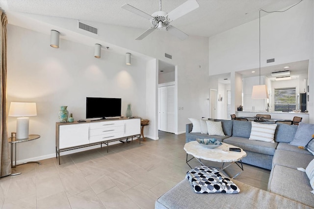 living room with a textured ceiling, high vaulted ceiling, and ceiling fan