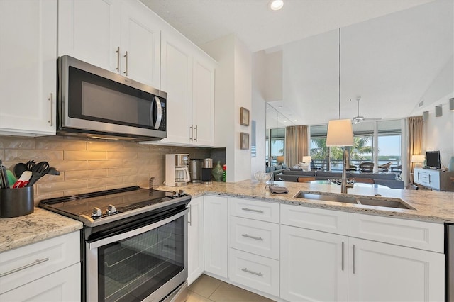 kitchen featuring appliances with stainless steel finishes, tasteful backsplash, white cabinetry, light tile patterned floors, and light stone counters