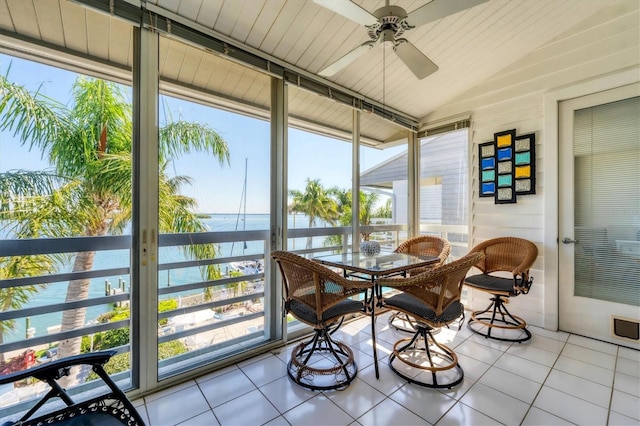 sunroom / solarium featuring lofted ceiling, ceiling fan, and a water view