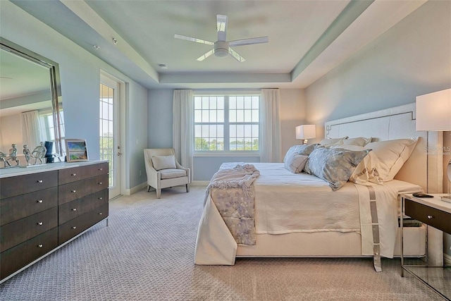 carpeted bedroom with a raised ceiling, ceiling fan, and access to outside