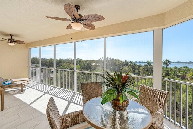 sunroom / solarium featuring ceiling fan and a water view