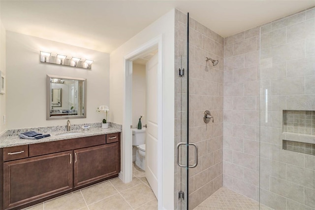 bathroom with tile patterned flooring, vanity, toilet, and walk in shower