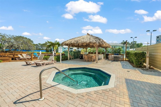 view of pool with exterior bar, a gazebo, a hot tub, and a patio area