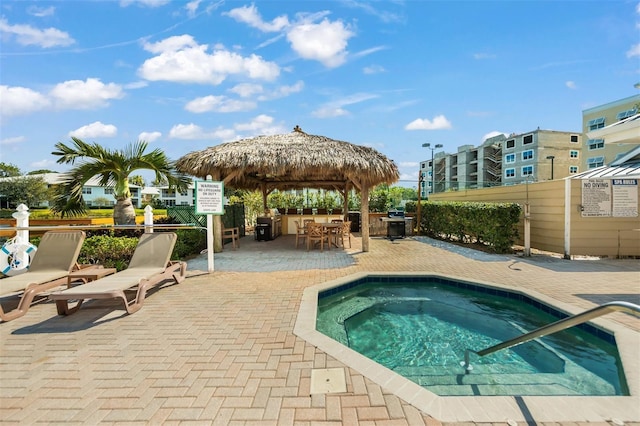 view of pool featuring a gazebo, a community hot tub, an outdoor bar, and a patio