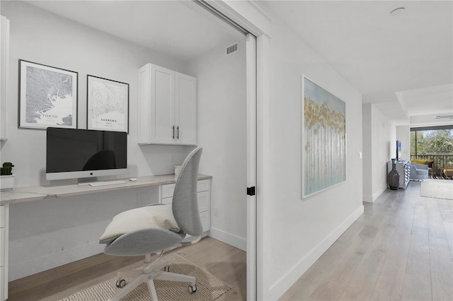 home office featuring light wood-type flooring, visible vents, and baseboards