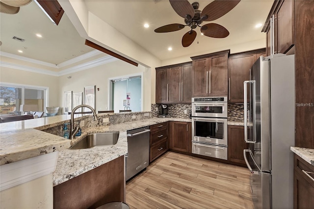 kitchen featuring a sink, stainless steel appliances, light wood-style floors, backsplash, and a warming drawer