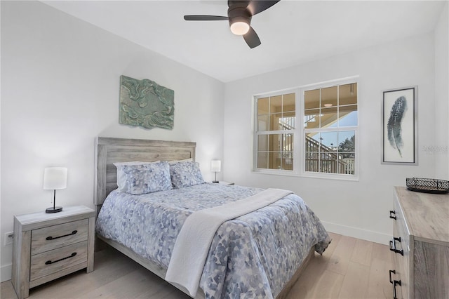 bedroom with light wood finished floors, baseboards, and a ceiling fan