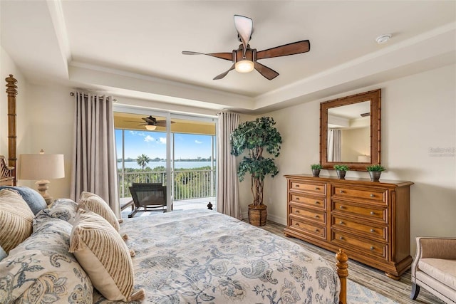 bedroom featuring access to outside, a raised ceiling, ceiling fan, and light hardwood / wood-style floors