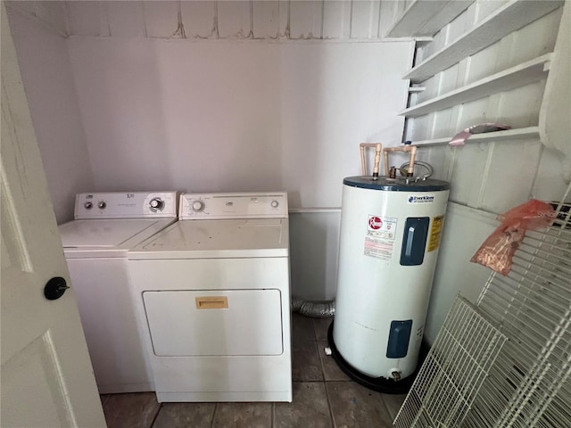 washroom with washing machine and clothes dryer, electric water heater, and dark tile patterned flooring