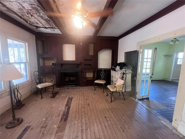 living area with ceiling fan, wooden walls, and wood-type flooring