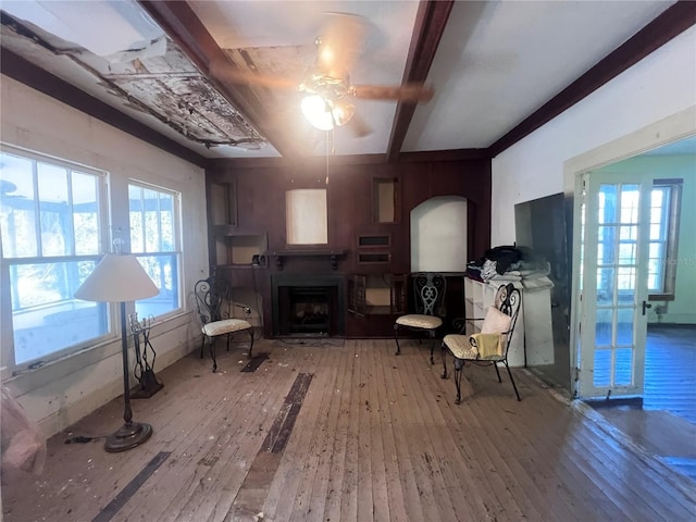 living area featuring beam ceiling, a healthy amount of sunlight, ceiling fan, and wood-type flooring