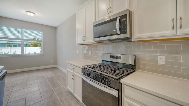 kitchen with white cabinets, stainless steel appliances, light tile patterned floors, and tasteful backsplash