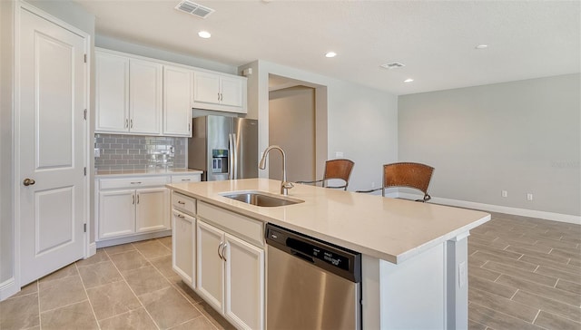 kitchen with sink, white cabinets, an island with sink, decorative backsplash, and stainless steel appliances