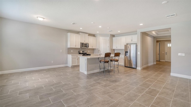 kitchen with appliances with stainless steel finishes, sink, white cabinetry, a kitchen island with sink, and a breakfast bar area