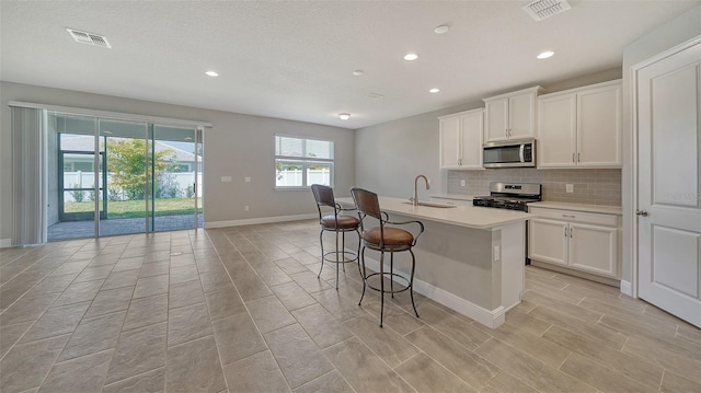 kitchen featuring sink, a center island with sink, white cabinets, and stainless steel appliances