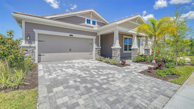 craftsman-style house with an attached garage, stone siding, and decorative driveway