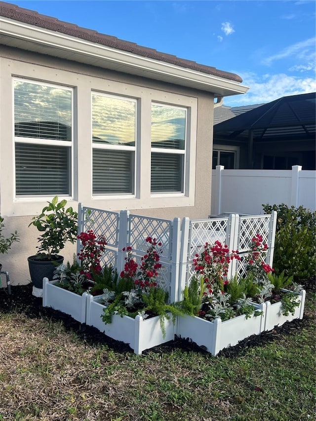 view of home's exterior with a vegetable garden, fence, and stucco siding