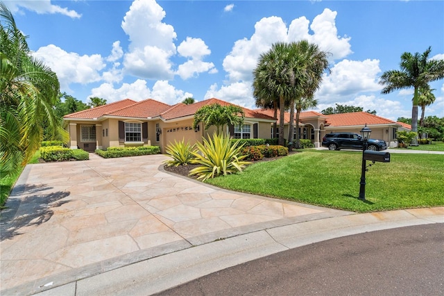 mediterranean / spanish home featuring a garage and a front lawn