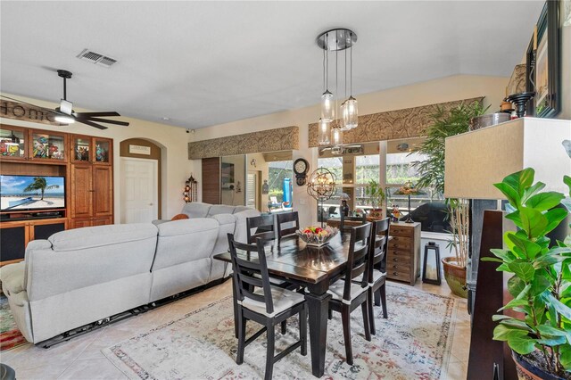 tiled dining area with ceiling fan with notable chandelier and vaulted ceiling