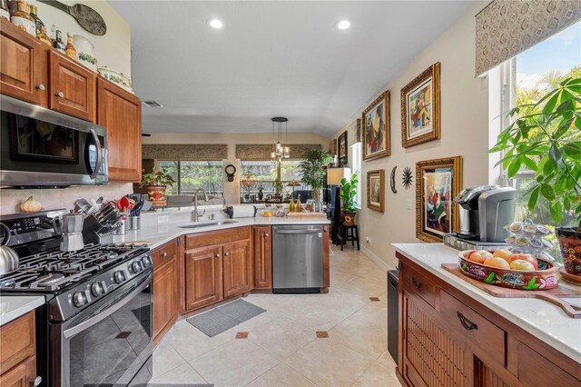 kitchen with light tile patterned floors, backsplash, appliances with stainless steel finishes, decorative light fixtures, and sink