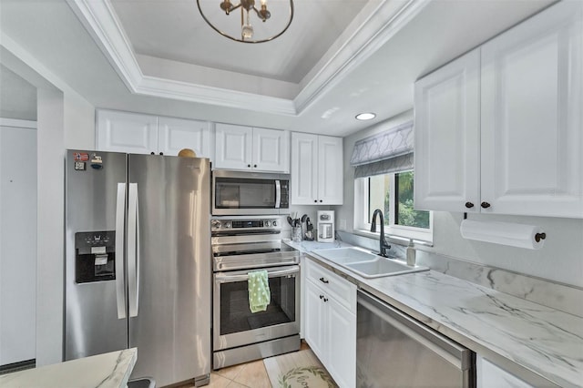 kitchen with appliances with stainless steel finishes, light tile flooring, a tray ceiling, white cabinets, and sink