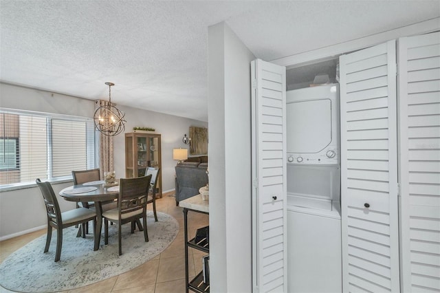 dining space featuring a textured ceiling, stacked washer / drying machine, and a chandelier