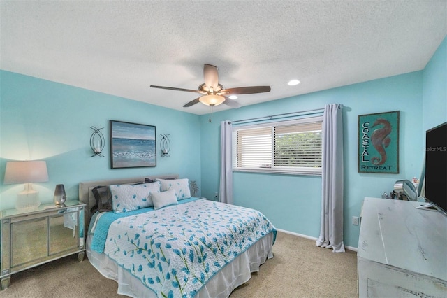 bedroom featuring light colored carpet, ceiling fan, and a textured ceiling