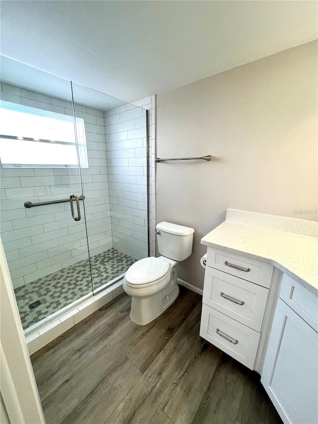 bathroom featuring toilet, vanity, wood-type flooring, and walk in shower