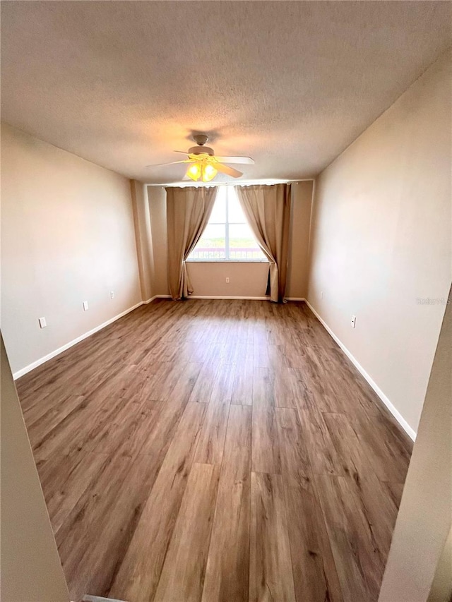 empty room featuring hardwood / wood-style flooring, ceiling fan, and a textured ceiling