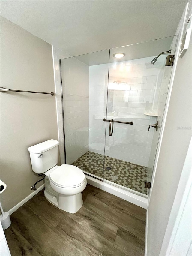 bathroom featuring wood-type flooring, toilet, and an enclosed shower