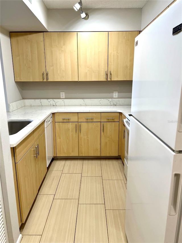 kitchen with light brown cabinets, white appliances, and sink