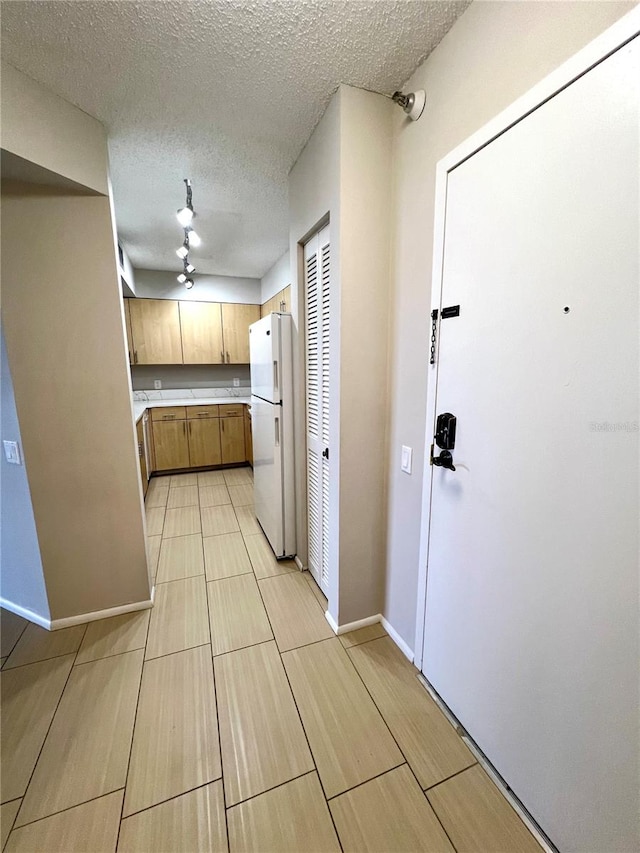 kitchen featuring a textured ceiling, white fridge, and ceiling fan