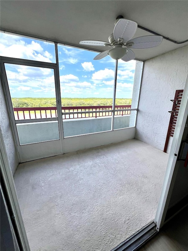 unfurnished sunroom with ceiling fan