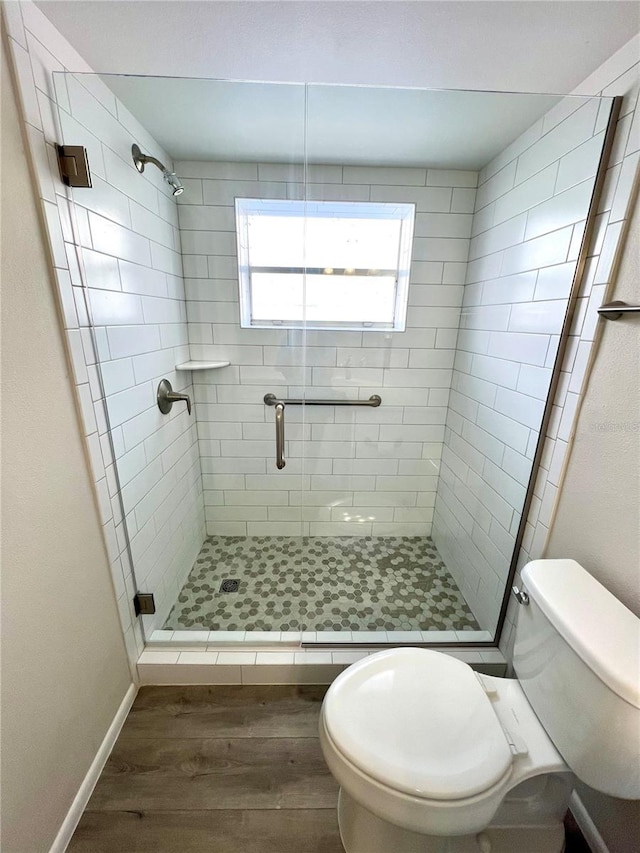 bathroom featuring hardwood / wood-style flooring, toilet, and walk in shower